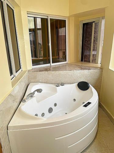 a white bath tub in a bathroom with two windows at Axion Hotel in Owerri
