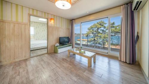 a room with a bed and a television and a table at tongyeong haegando pension in Tongyeong