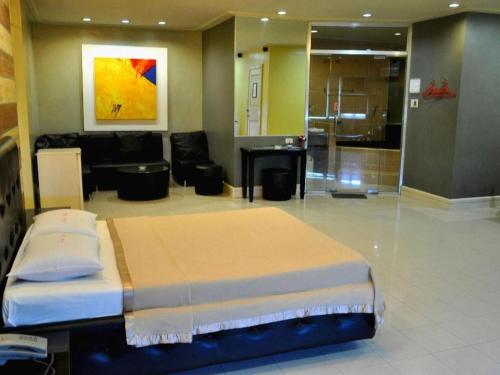 una habitación con una cama y una sala de estar en Jardin de Rosal Hotel, en Manila