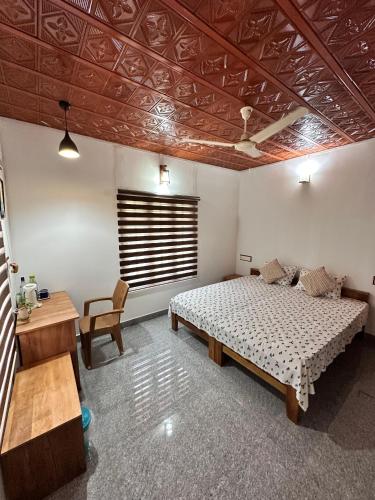 a bedroom with a bed and a table and a desk at Avocado Orchards - Home Stay in Kenichira