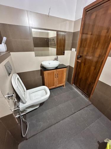 a bathroom with a sink and a toilet and a mirror at Avocado Orchards - Home Stay in Kenichira