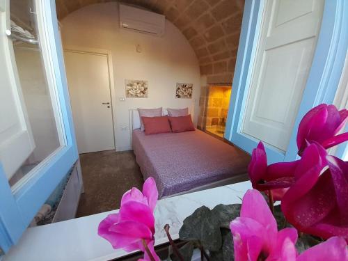 een kamer met een bed met roze bloemen op de voorgrond bij Casa Ninu' in Maruggio
