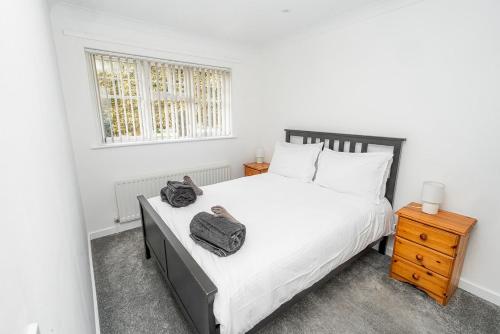ein Schlafzimmer mit einem großen Bett und einem Nachttisch in der Unterkunft Modern Two Bedroom Home with Parking in Sherborne Saint John