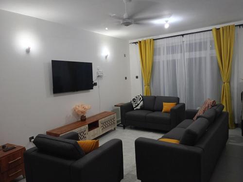 een woonkamer met twee banken en een flatscreen-tv bij Tausi Home in Mombasa