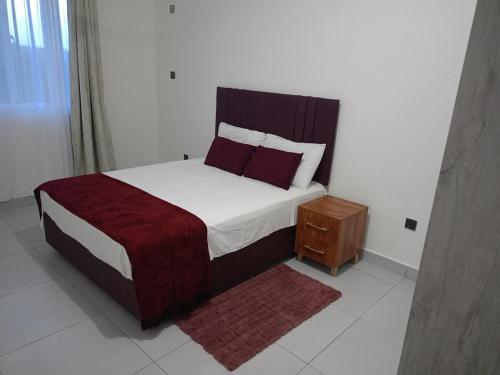 een slaapkamer met een groot bed en een nachtkastje bij Tausi Home in Mombasa