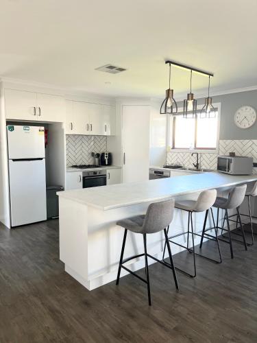 a kitchen with a large white counter and chairs at Telopea House Mount Gambier in Worrolong