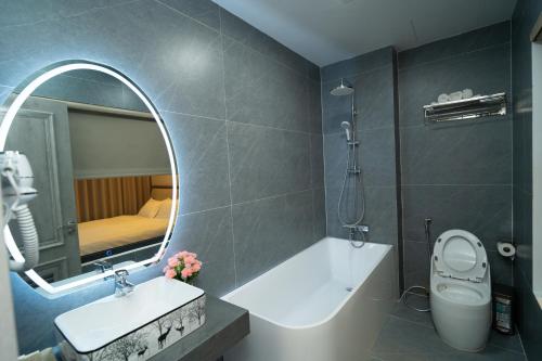 ein Badezimmer mit Badewanne, Waschbecken und Spiegel in der Unterkunft T-Moon Homestay in Binh Hai