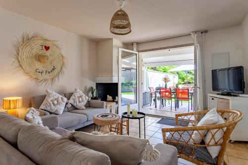 ein Wohnzimmer mit Sofa und Fernseher in der Unterkunft Villa Rose des Sables, 100m de la Plage et Centre in Lège-Cap-Ferret