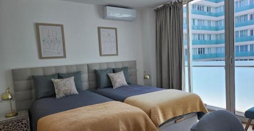 a bedroom with a bed and a large window at Downtown Funchal Bohemian Charm in Funchal