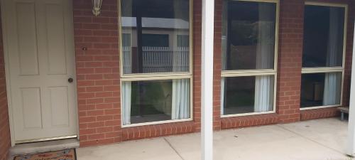 een bakstenen gebouw met ramen en een witte deur bij Margarets Lane in Warrnambool