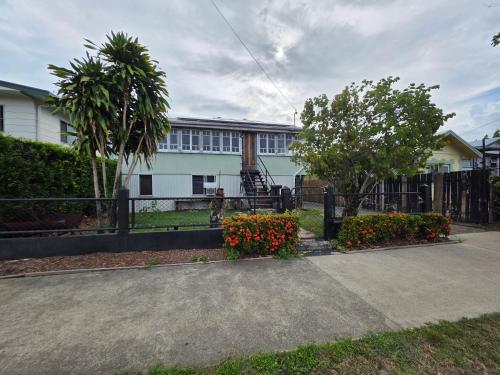 a building with a fence and flowers in a yard at Buchan Street, Accommodation in East Trinity