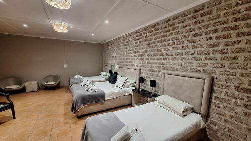 Habitación con 3 camas y pared de ladrillo en Mariental Hotel Cc, en Mariental