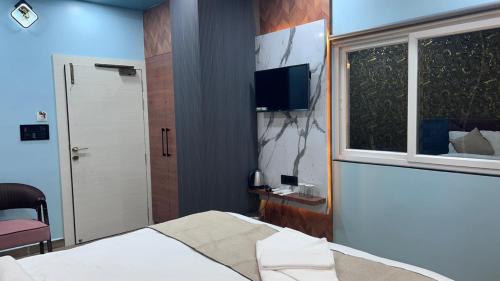 a bedroom with a bed and a window and a television at Hotel Rashmi Grand in Khagaria