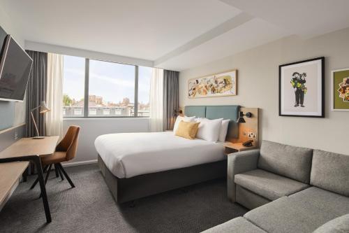 a hotel room with a bed and a couch at Holiday Inn London Bloomsbury by IHG in London