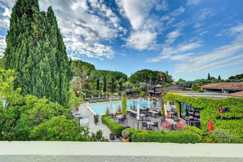 Una vista de una piscina con árboles y arbustos. en Best Western Sévan Parc Hôtel, en Pertuis