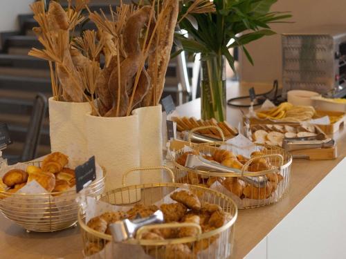 a table topped with baskets of bread and pastries at Novotel Medellin El Tesoro in Medellín
