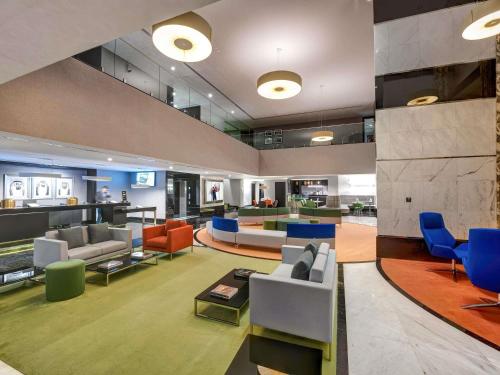 シャルジャにあるNovotel Sharjah Expo Centreの建物内のソファと椅子のあるロビー