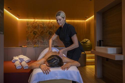 BagnaiaにあるElbitat Homes Wellness&Spaの男のベッドマッサージを行う女