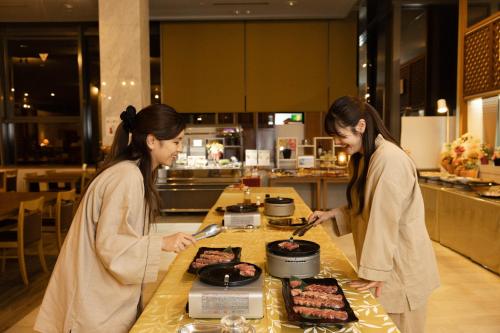 two women standing in a kitchen preparing food at 9stayリゾートテクノポート福井 in Sakai
