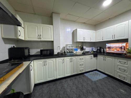 a large kitchen with white cabinets and appliances at Bed space for Budget Backpacker - No Parking in Abu Dhabi