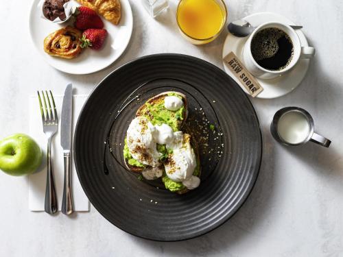 キャンベラにあるMercure Canberra Belconnenの食べ物の皿とコーヒーカップが置かれたテーブル