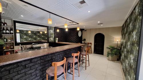 Una barra con taburetes en una habitación con una pared de ladrillos. en Mariental Hotel Cc, en Mariental