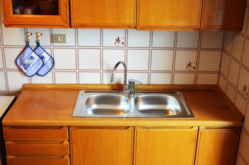 een keuken met een roestvrijstalen wastafel en houten kasten bij Casa Furletti Holiday Home in Tenno