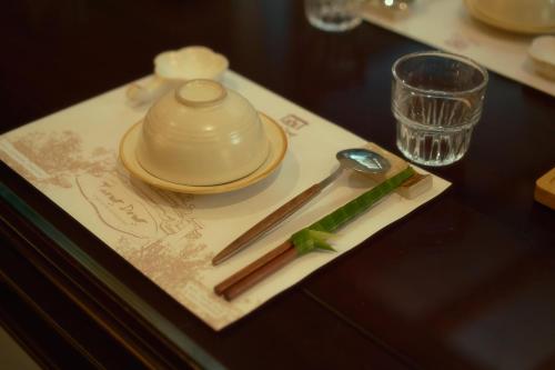 a table with a plate with a tea pot and spoon at Thong Dong Quán Boutique Hotel Hue in Hue