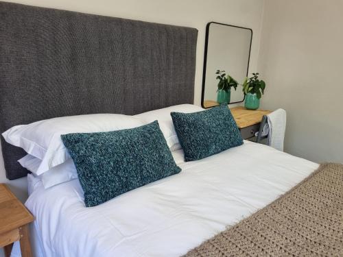 Una cama blanca con dos almohadas verdes encima. en One on Old Main - Unit 2, en Hillcrest