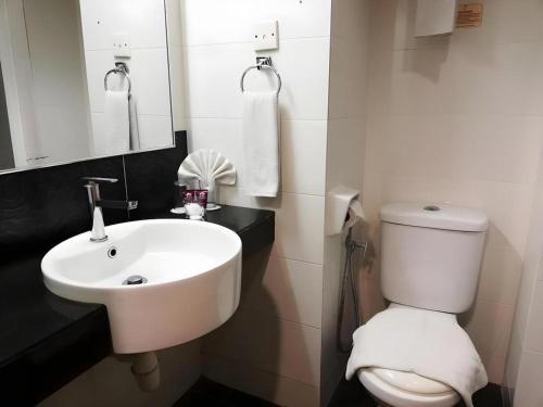 a bathroom with a white sink and a toilet at Grand Barakah Hotel in Kuala Lumpur
