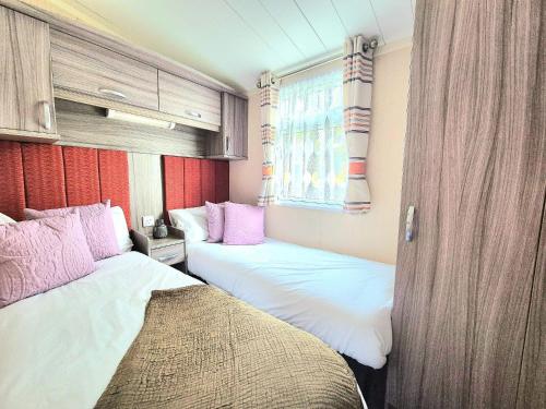 2 Betten in einem Zimmer mit rosa und weiß in der Unterkunft Lovely Caravan With Decking At Cherry Tree Park Norfolk Ref 70724C in Belton