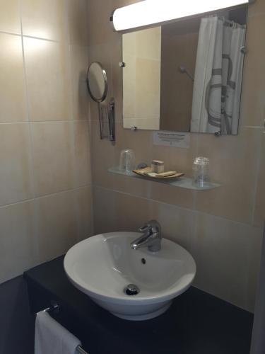 a bathroom with a white sink and a mirror at Logis Hôtel Le Manoir & Lounge in Apt