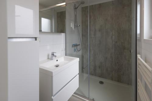 a white bathroom with a sink and a shower at Vakantiepark de Boomgaard in Westkapelle