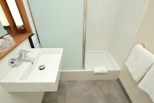 a white bathroom with a sink and a shower at Campanile Arras - Saint-Nicolas in Saint-Nicolas