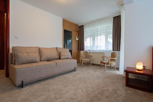 una sala de estar con un sofá y una mesa en Divski Wellness Resort, en Divčibare