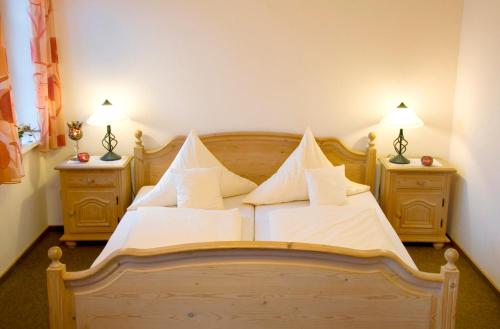 a bedroom with a wooden bed with white pillows at Gasthof Sommer in Lautertal