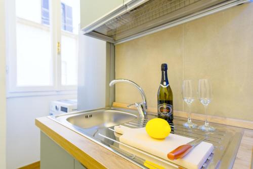 una cocina con fregadero y una botella de vino en Elegantis Pompeo Magno Suite Apartment - Historic Center near the Vatican and Piazza del Popolo, en Roma