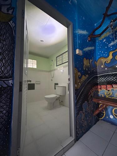 een badkamer met een toilet en een muur met een schilderij bij Chill Out Bar and Jungle Bungalows in Krabi town