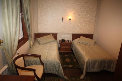 a small room with two beds and a chair at Vila Sigal Pogradec in Pogradec