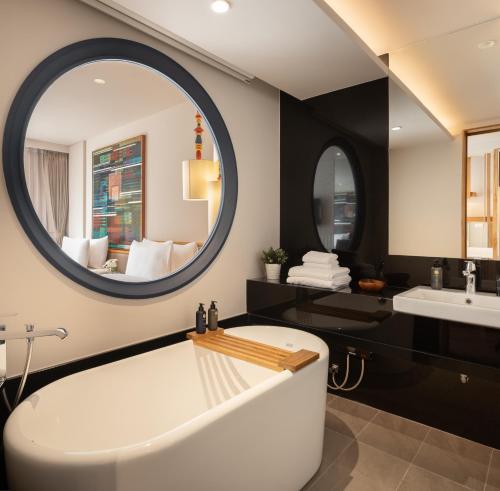 a bathroom with a tub and a large mirror at Na U Hotel in Chiang Mai