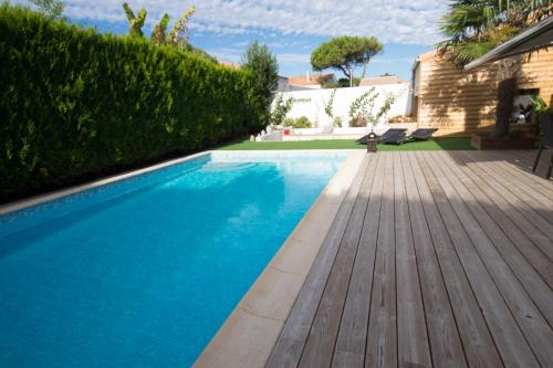 une piscine avec une terrasse en bois à côté d'une maison dans l'établissement ré tour de plage, à Saint-Martin-de-Ré