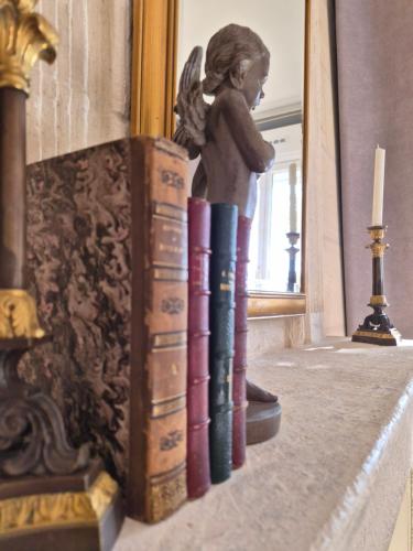 Eine Statue eines kleinen Mädchens, das auf einem Bücherstapel sitzt in der Unterkunft Chambre Bordeaux, piscine et spa in Lugon et l’Ile du Carney