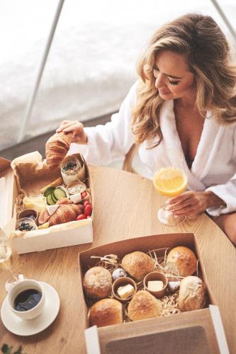 een vrouw zit aan een tafel met een doos gebakjes bij Sense Resort in Maruszyna