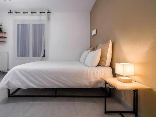 a bedroom with a bed and a table with a lamp at Pleasant, cozy studio with pool 2 mins from Montpellier in Juvignac