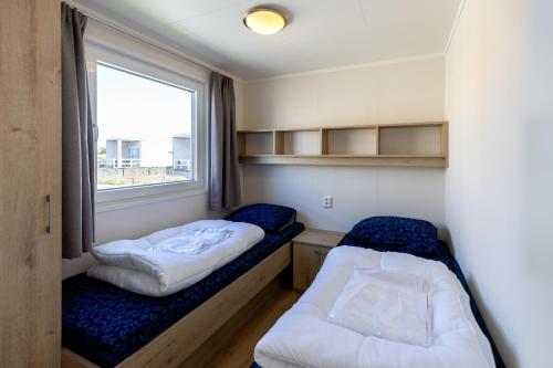 a small room with two beds and a window at Vakantiepark de Boomgaard in Westkapelle