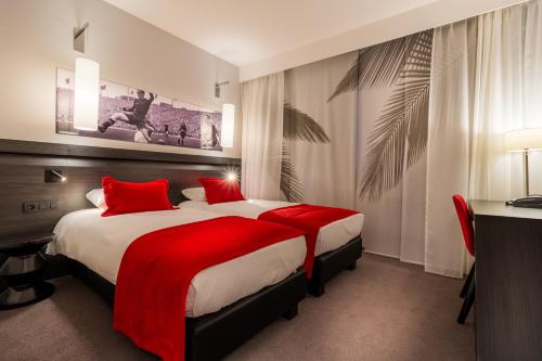 um quarto de hotel com uma cama grande com almofadas vermelhas em Martin's Red em Tubize