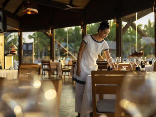 a woman standing in a restaurant preparing food at Kuredhivaru Resort and Spa - Maldives in Manadhoo