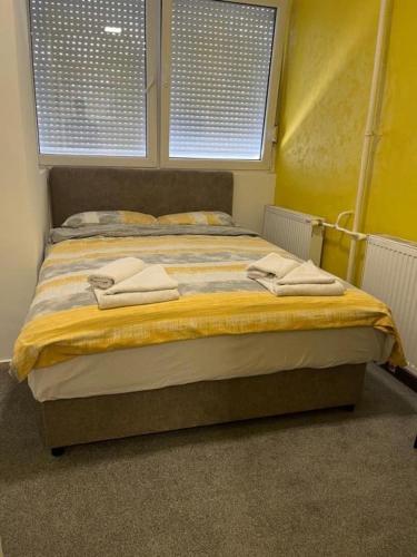 un grande letto in una stanza con due finestre di Old Town Rooms a Novi Sad