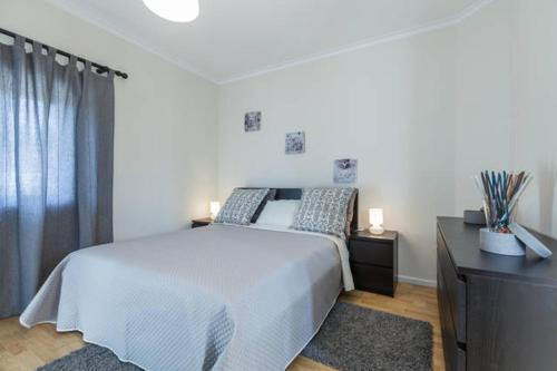 a bedroom with a large white bed and a dresser at Carvalhosa Apartment in Monte