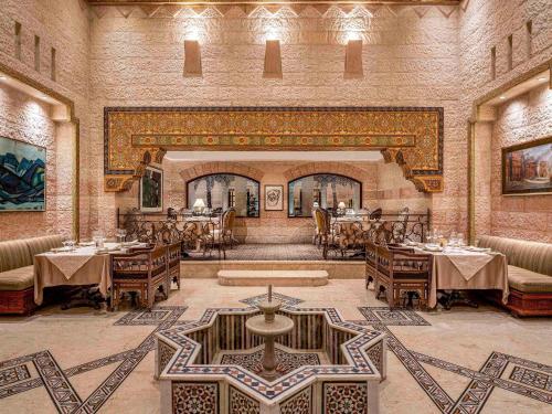 um restaurante com mesas e cadeiras em uma sala em Mövenpick Resort Petra em Wadi Musa